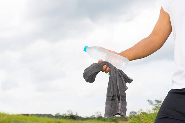 Mann mit Wasserflasche und Handtuch in der Hand und Naturhintergrundbild. - Foto, Bild