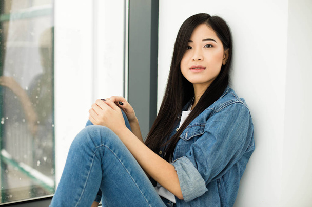 asian girl sitting on the floor next to a window - Photo, image