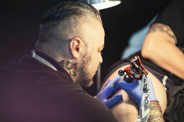 Un tizio si sta facendo un tatuaggio, in uno studio
. - Foto, immagini