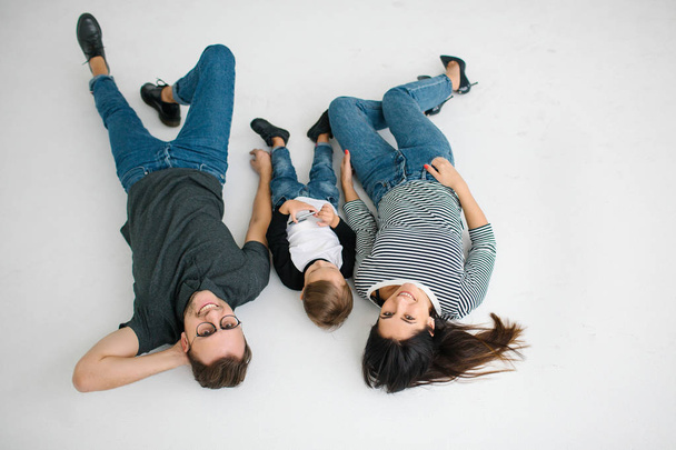 Hipster father, mother lying with baby boy on white background - Фото, зображення