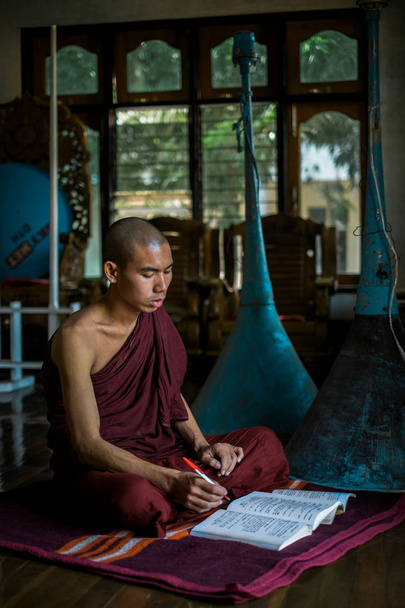 Μοναχός κάθεται στο χαλί με ανοιχτό βιβλίο - Φωτογραφία, εικόνα
