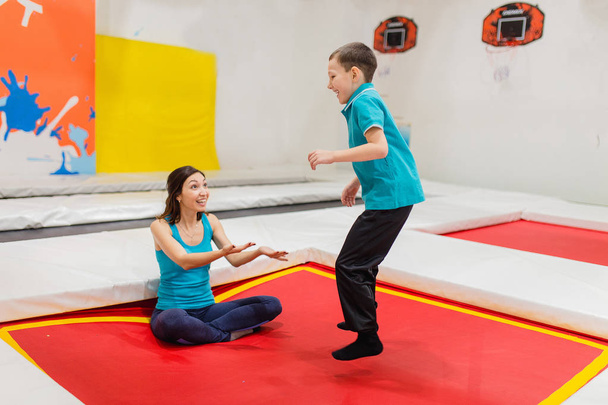 Madre allenatore formazione suo figlio a saltare sul trampolino nel moderno centro fitness e volare
 - Foto, immagini