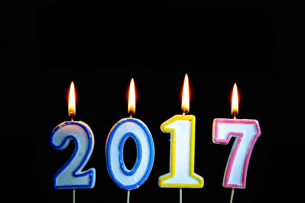 Candela colorata dell'anno 2017 con illuminazione a fiamma sul nero
 - Foto, immagini