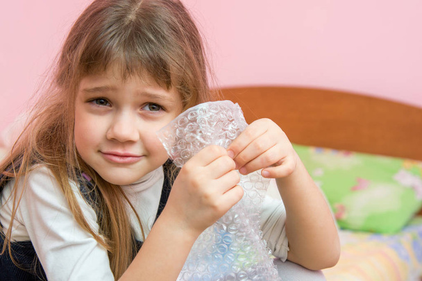 Fünfjähriges Mädchen hört zu, wie Blasen auf der Verpackung platzen - Foto, Bild