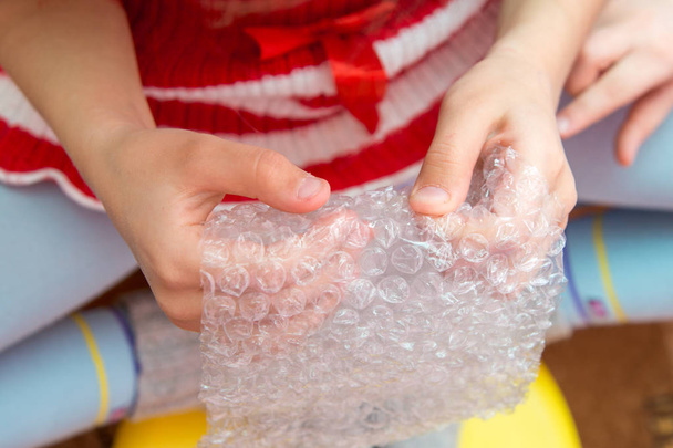 Top view of the child 's hands pressing the bubbles on the packaging film
 - Фото, изображение