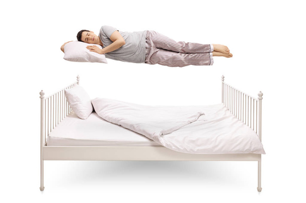 man sleeping and floating above a bed - Photo, Image