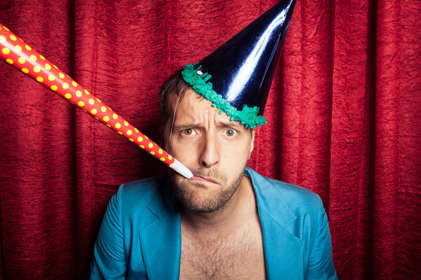 caucasian sad man with party hat on red background  - Foto, Bild