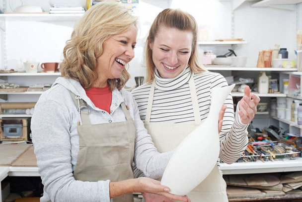 Mature Woman With Teacher Looking At Vase In Pottery Class - Photo, Image