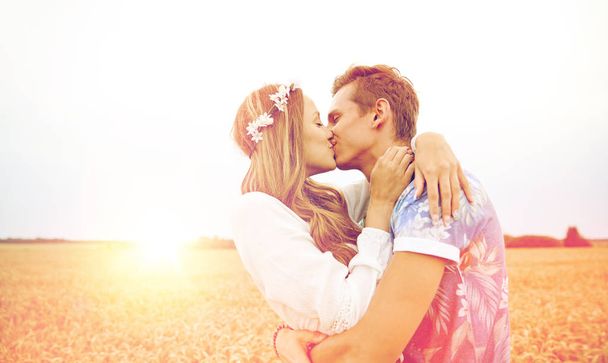 happy young hippie couple kissing in field - Photo, Image