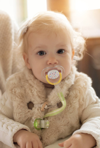 Cute baby girl with a pacifier in her mouth - Foto, Imagen