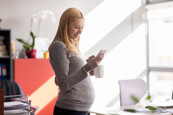 pregnant businesswoman with smartphone at office - Zdjęcie, obraz