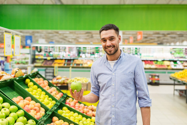 happy man buying green apples at grocery store - Photo, image