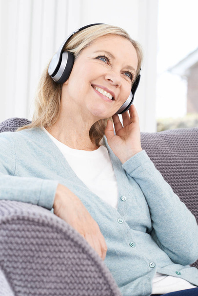 Mature Woman Listening To Music On Wireless Headphones - Zdjęcie, obraz
