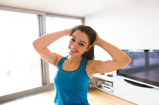 Young woman exercising at home, stretching neck. - Foto, Imagem