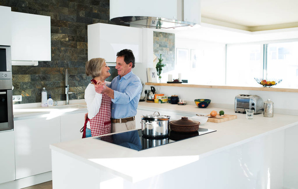 Senior couple in the kitchen cooking and dancing together. - Foto, Imagen