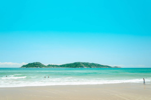 Campeche strand: mensen spelen op het strand met een groene water en een eiland op de achtergrond - Foto, afbeelding