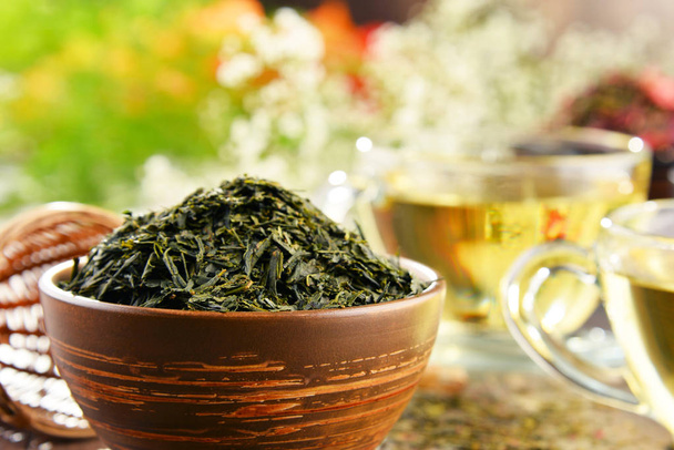 Samenstelling met kop van thee en kommen van thee bladeren - Foto, afbeelding