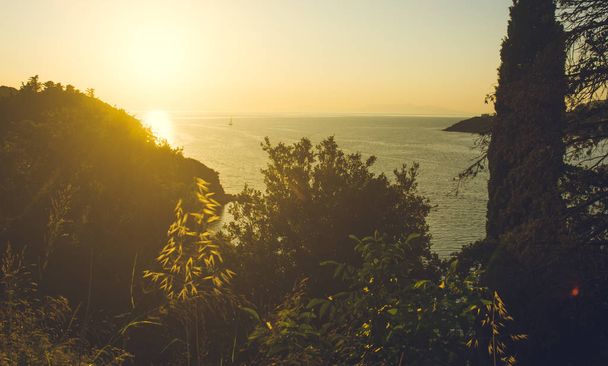 Puesta de sol sobre el mar detrás de la colina
 - Foto, imagen