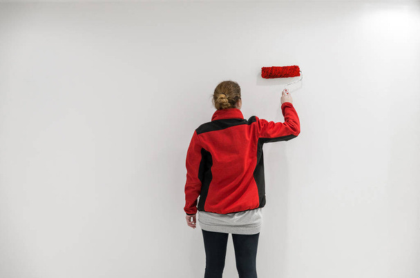 Female painter with red paint roller in front of wall as templat - Zdjęcie, obraz