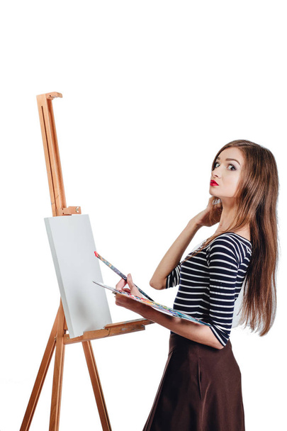 Schattige mooie meisje kunstenaar schilderen van een foto op canvas ezel. Ruimte voor tekst. Studio witte achtergrond, geïsoleerd. - Foto, afbeelding