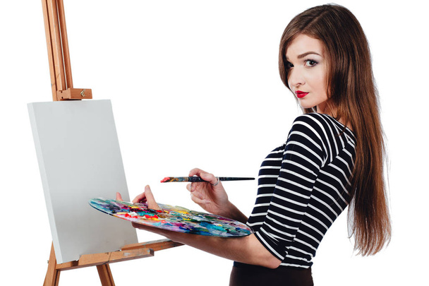 Cute beautiful girl artist painting a picture on  canvas  easel. Space for text. Studio white background, isolated. - Foto, Imagem