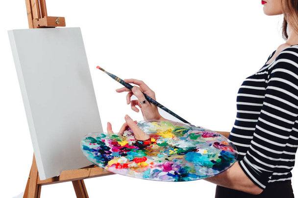 Roztomilá krásná dívka umělec maluje obraz na plátně stojanu. Prostor pro text. Studio bílé pozadí, izolované. - Fotografie, Obrázek