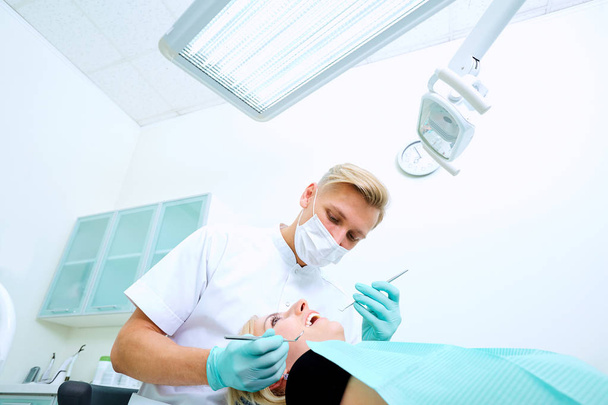 The dentist treats a patient  mask in  dental office - Foto, Bild