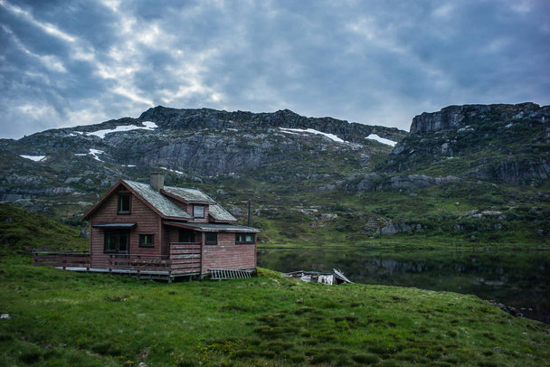 Antigua casa en lago noruego y cielo dramático
 - Foto, Imagen