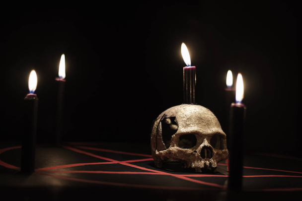 Black MagicSkull and candle on old book on dark color background - Photo, Image