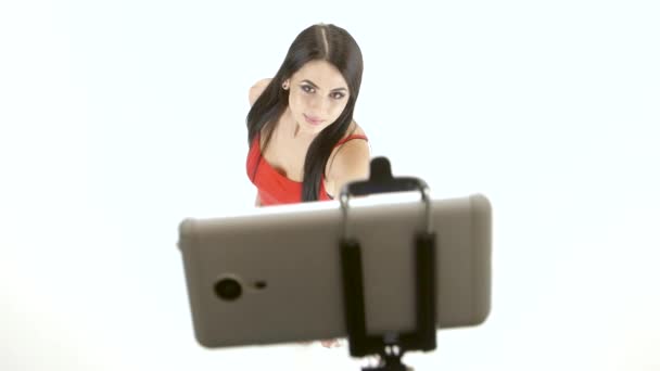 Brunette girl doing selfie photos using a smartphone and monopod - Filmati, video