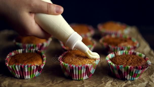 Cupcake versieren. Handen met spuitzak gevuld met slagroom - Video