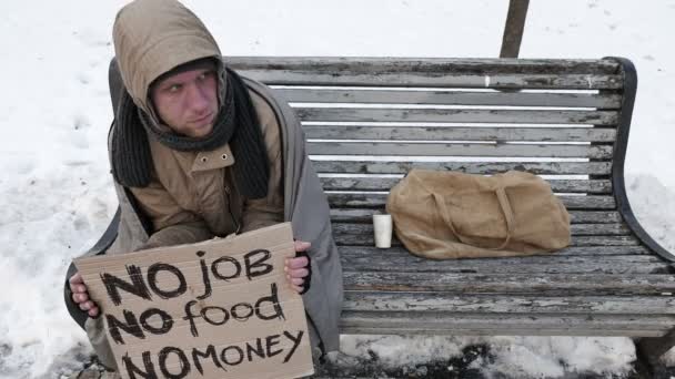  4K.unemployment człowiek siedzieć na ławce w parku miejskim w zimie. Problem życia młodzieży - Materiał filmowy, wideo
