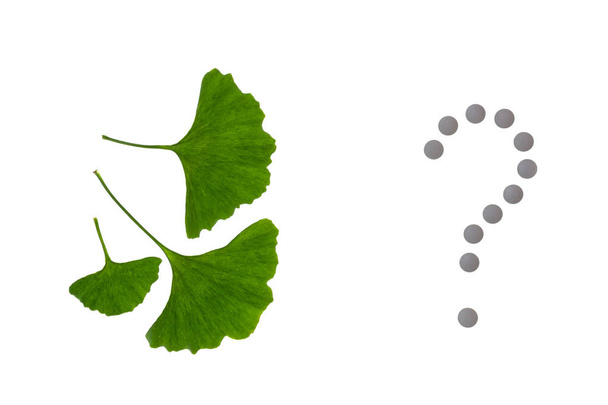 Ginkgo biloba Blätter mit Pillen Fragezeichen auf weißem Hintergrund - Foto, Bild