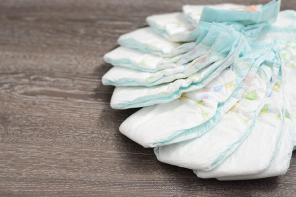 Pile or stack of baby diapers isolated on wooden floor - Photo, Image