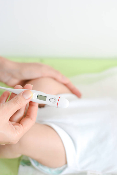 Checking baby temperature which indicates high fever on thermometer - Foto, afbeelding