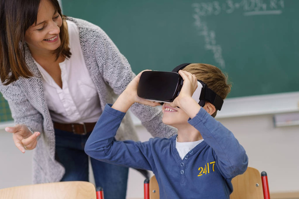 Smiling teacher watching a boy in VR goggles - Foto, Imagem