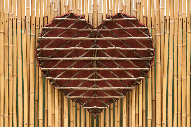 Ξύλινη χειροποίητη καρδιά σε τοίχο από μπαμπού - Φωτογραφία, εικόνα