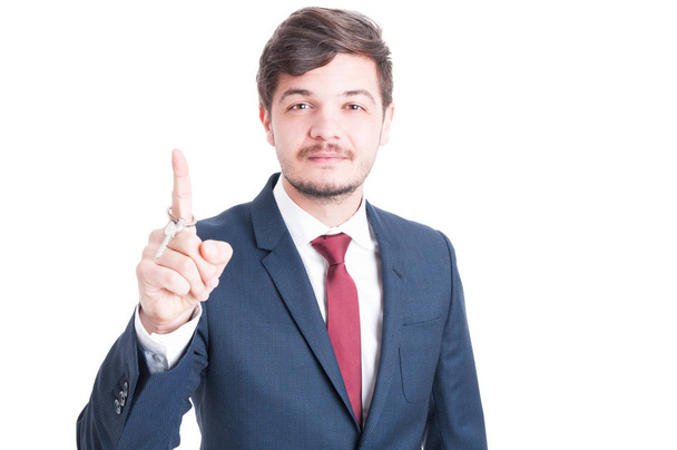 Real estate agent wearing suit holding key and rolling it - Fotó, kép