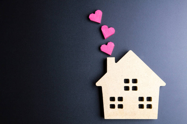 Maison en bois jouet et boîte en papier rouge forme de coeur sur backgrou noir
 - Photo, image