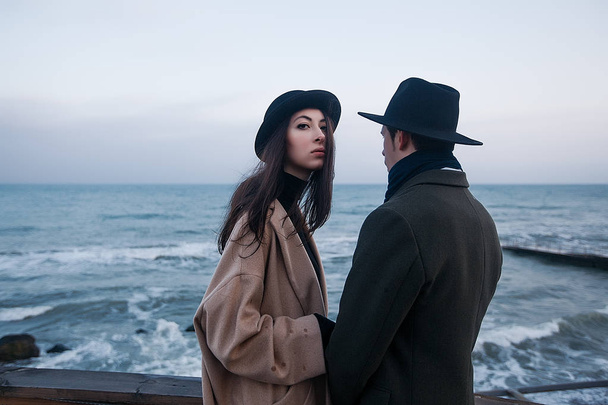 pareja en abrigos y sombreros de pie en la terraza
 - Foto, imagen