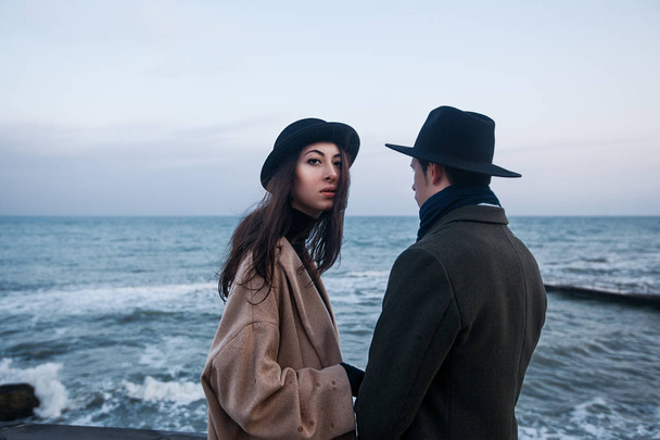 pareja en abrigos y sombreros de pie en la terraza
 - Foto, imagen