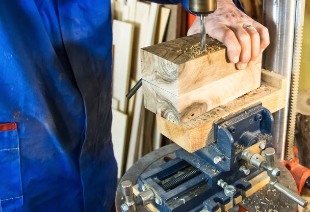 Ξυλουργός χώρος εργασίας-άνθρωπος χρησιμοποιώντας ένα τρυπάνι πάτημα σε ξύλο.  - Φωτογραφία, εικόνα