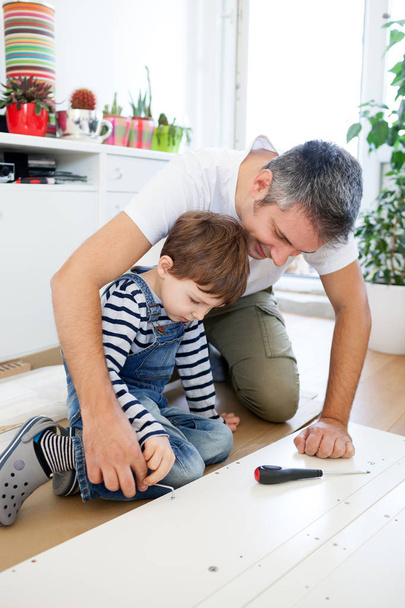 Father and son assembling furniture - 写真・画像