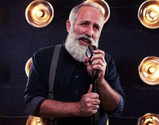 Artista apasionado cantando con un micrófono en una luz de estudio
 - Foto, imagen