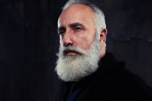 Портрет стильного красивого мужчины с бородой, позирующего в темноте
 - Фото, изображение