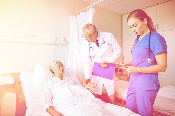 doctor and nurse visiting senior woman at hospital - Photo, Image