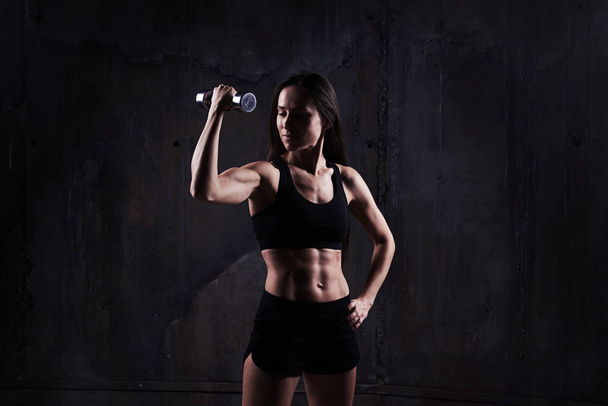 Jovem mulher muscular confiante fazendo bíceps enrolar com halteres
 - Foto, Imagem