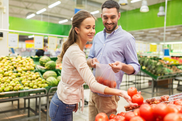 happy couple buying tomatoes at grocery store - Foto, Bild
