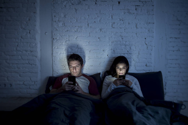 couple at home in bed late at night using mobile phone in relationship communication problem - Zdjęcie, obraz