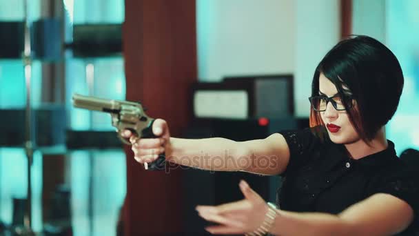 Tyttö brunette lasit mustat kehykset, tähtää kohde kädessään ase
. - Materiaali, video